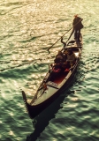 A venice gondola with tourists at sunset